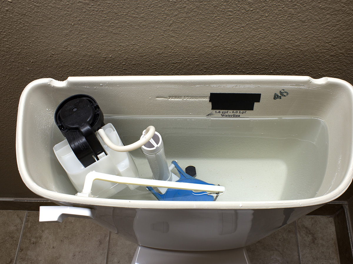 A toilet tank with its lid off