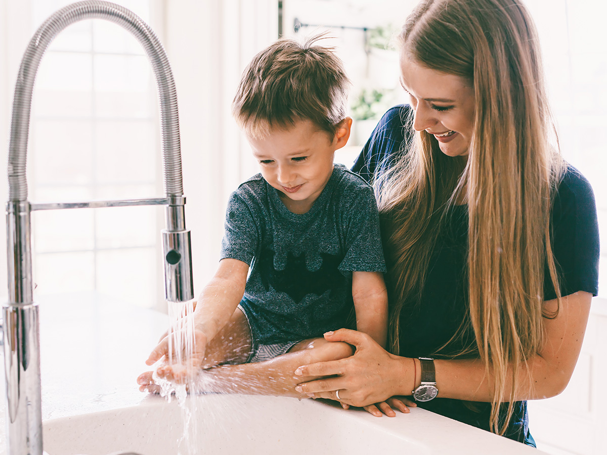 A mother and her son turning on the kitchen sink