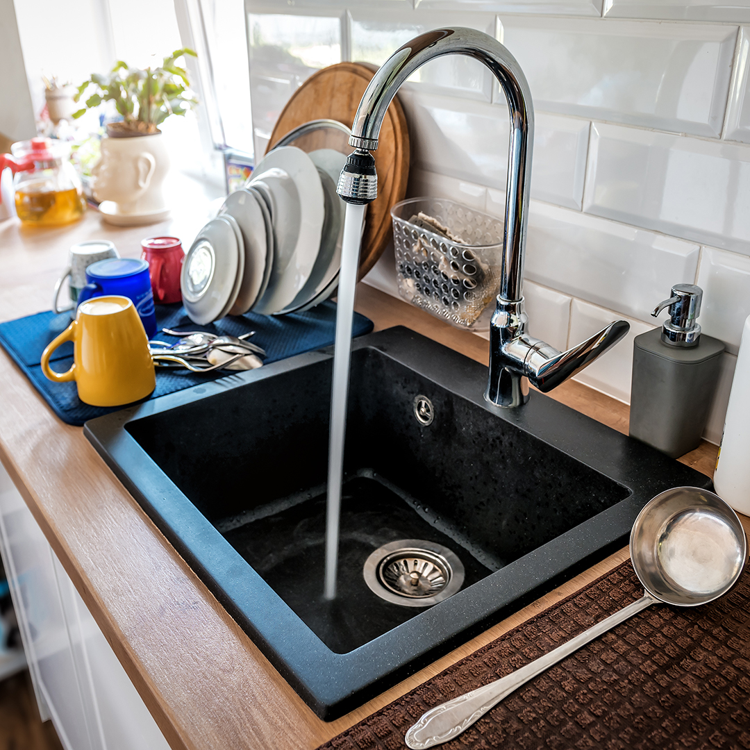 Water flowing out of a kitchen stainless steel tap into the sink