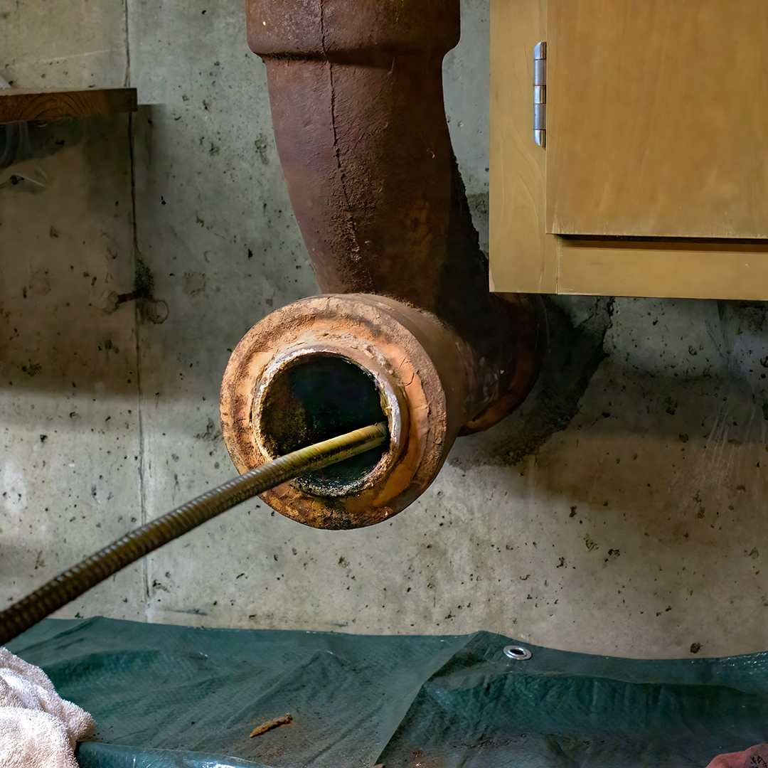 Hands of a plumber as he runs a camera scope and cleaning machin